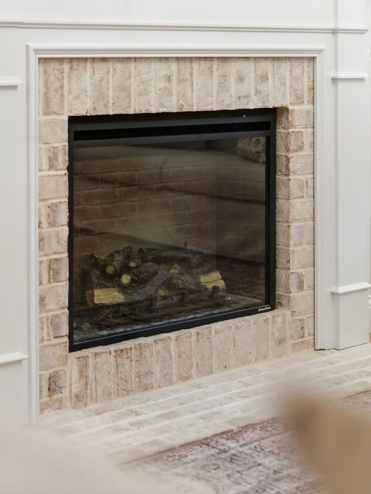 Fireplace with a whitewashed brick surround framed in white trim